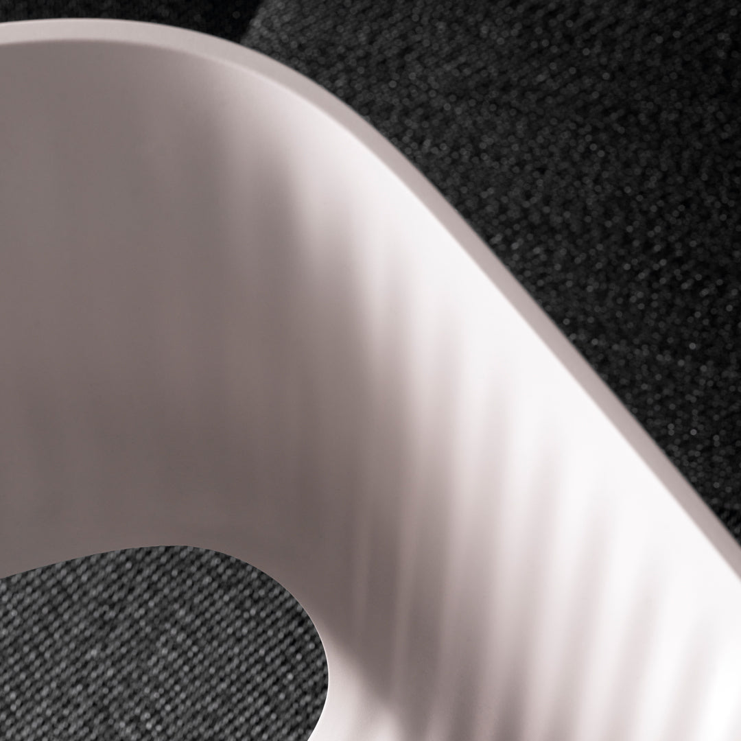Textured black surface juxtaposed with smooth pink curve, highlighting contrasting colors and patterns.