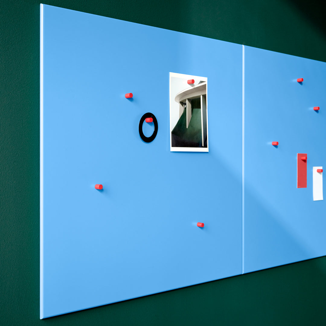 Blue wall board with red accents and a green background, featuring various attachments and a photo display.