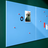 Blue wall board with red accents and a green background, featuring various attachments and a photo display.