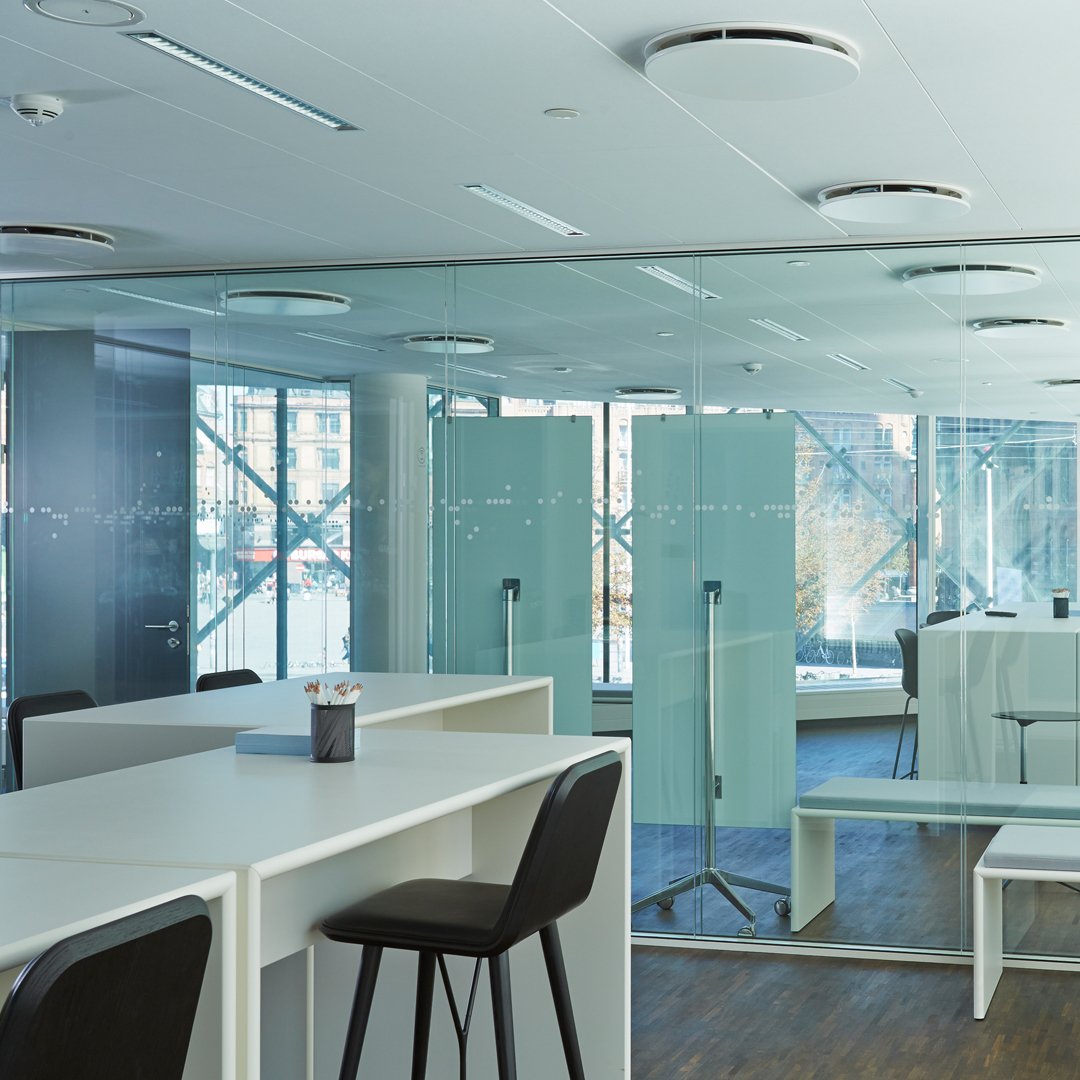 Modern workspace with light blue glass panels, white furniture, and natural wood flooring for a sleek, professional look.