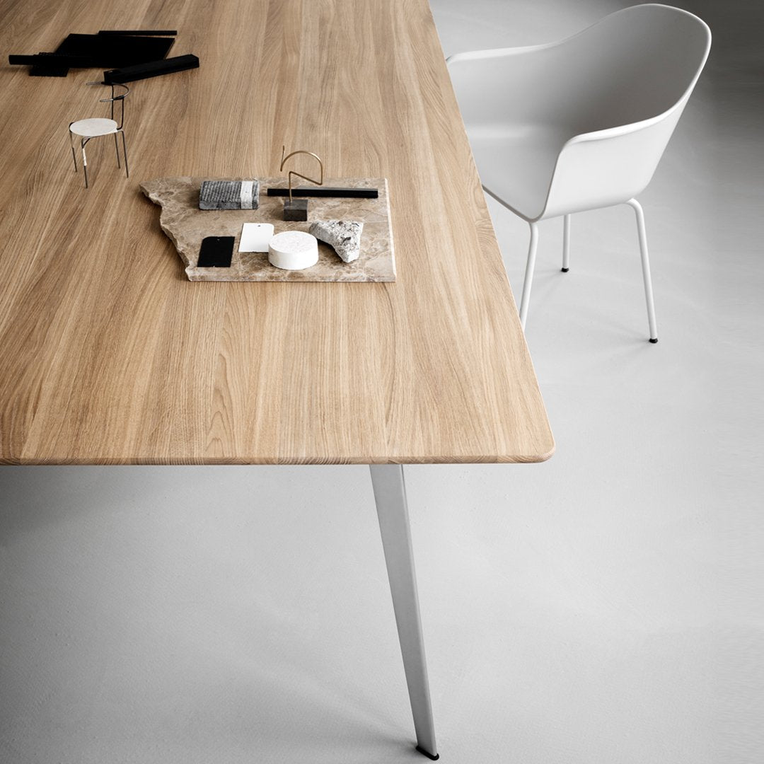 Light oak wood table with a smooth grain, featuring black and white decorative objects on a gray surface.