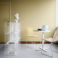 Modern interior with yellow and white chairs, a white wire shelf, and a light blue decorative sphere against a soft yellow wall.