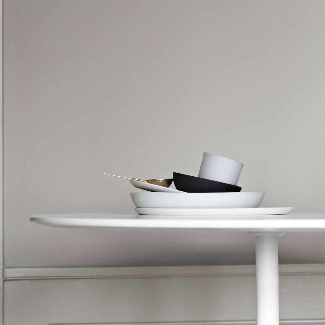 Stacked white and black dishware on a minimalist table with a smooth, neutral background. Elegant and modern aesthetic.