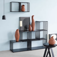 Black wire shelves with terracotta vases against a light blue wall, featuring geometric black and white patterns.