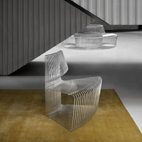 Clear acrylic chair with sleek, transparent lines against a soft golden rug and geometric backdrop.