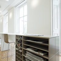 Modern office space featuring neutral beige walls, light wood flooring, and sleek white furniture accents.