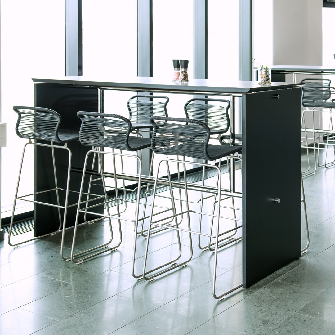 "Modern black bar with sleek silver stools featuring a minimalist design, accented by natural light."