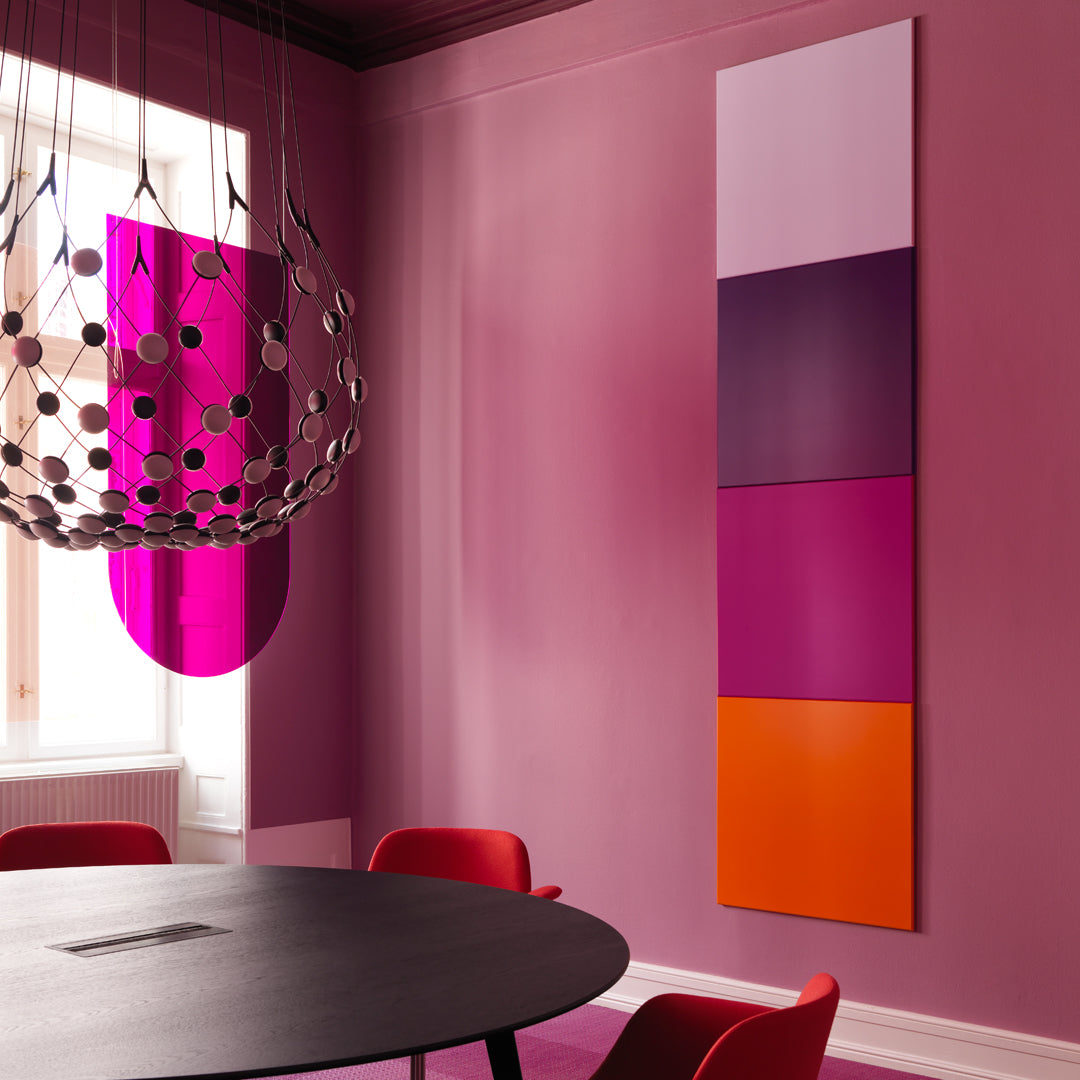 Colorful wall art featuring vibrant pink, purple, and orange panels against a soft pink background and black table.