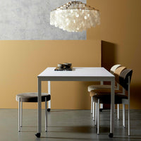 Stylish white dining table with patterned beige and brown chairs, set against a warm, golden-orange wall.