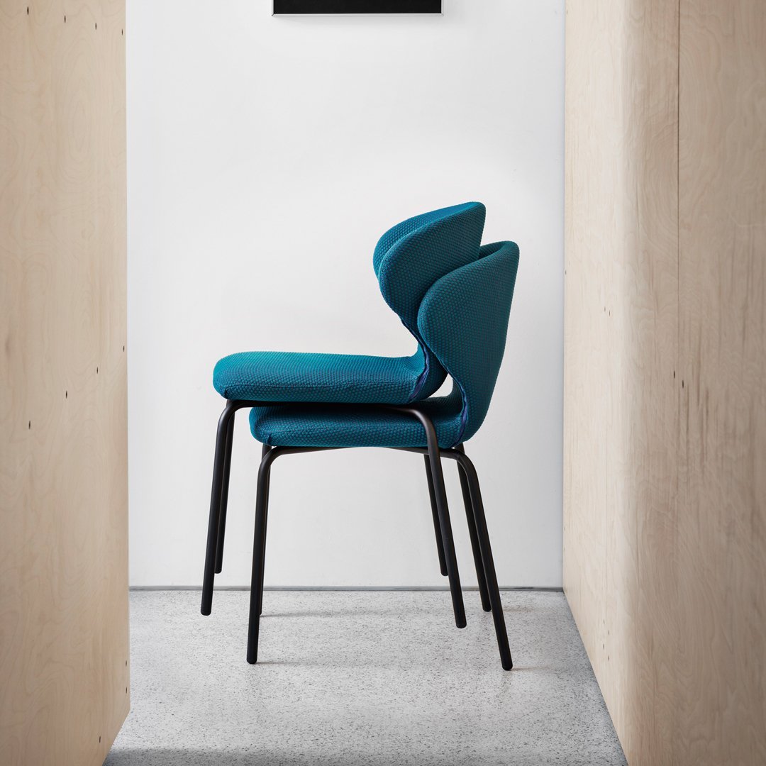 Stacked chairs featuring a vibrant teal upholstery and sleek black metal legs against a minimalist backdrop.