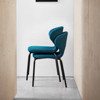 Stacked chairs featuring a vibrant teal upholstery and sleek black metal legs against a minimalist backdrop.