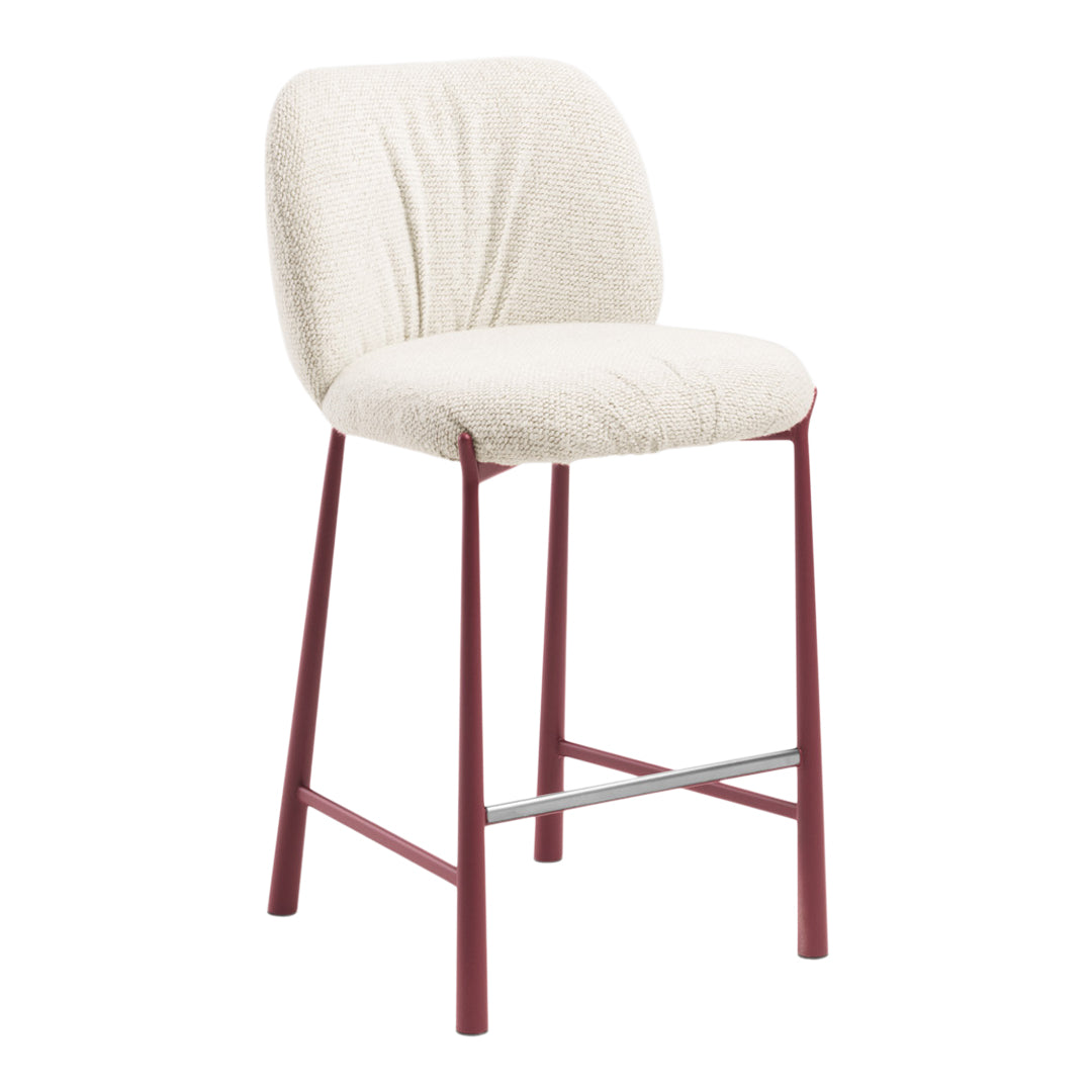 Cream upholstered bar stool with textured fabric and deep red metal legs. Stylish and modern design for any space.