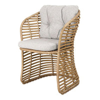 Natural rattan chair with soft gray cushion, featuring a modern woven design and stylish curved silhouette.