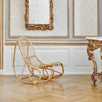 Natural rattan rocking chair in a light, airy room with white and gold accents, featuring elegant flooring and ornate details.