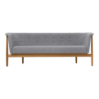 Gray upholstered sofa with button detailing and wooden legs, showcasing a modern, minimalist design.