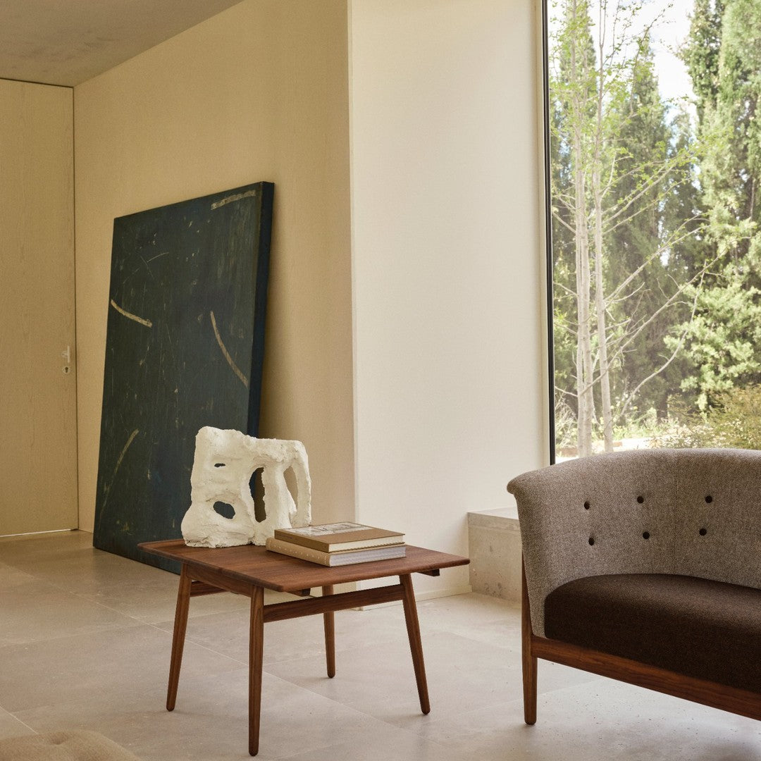 Modern minimalist room featuring a dark blue wall art with golden accents, a light beige sofa, and a wooden coffee table.