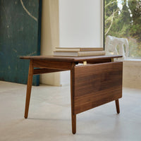 Walnut wood drop-leaf table with a smooth, natural finish and tapered legs, perfect for contemporary decor.