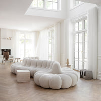White tufted modular sofa in a bright, airy room with large windows and light wood flooring. Modern, minimalist design.