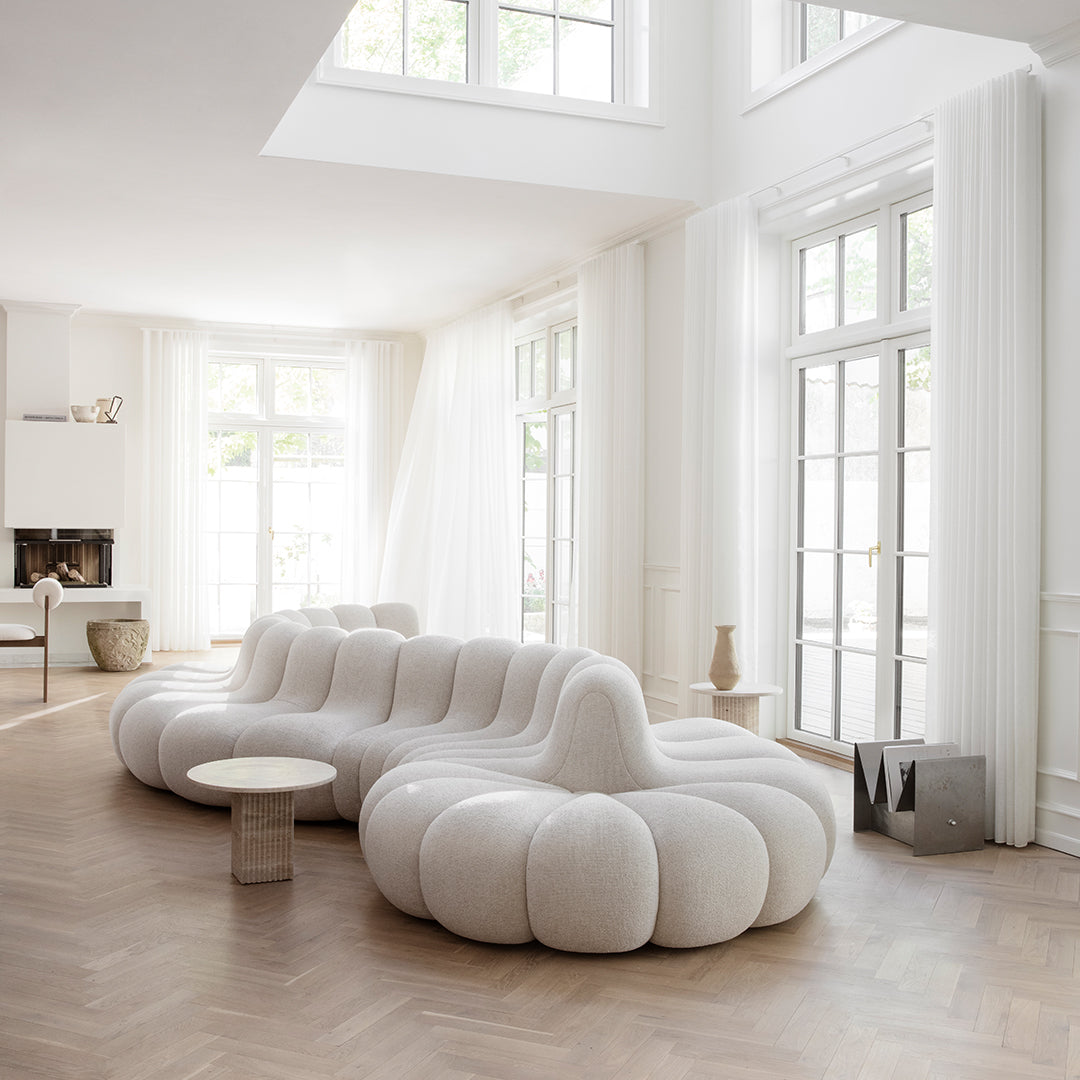 Curvy white sofa with plush, cloud-like pattern in a bright, airy room featuring natural light.