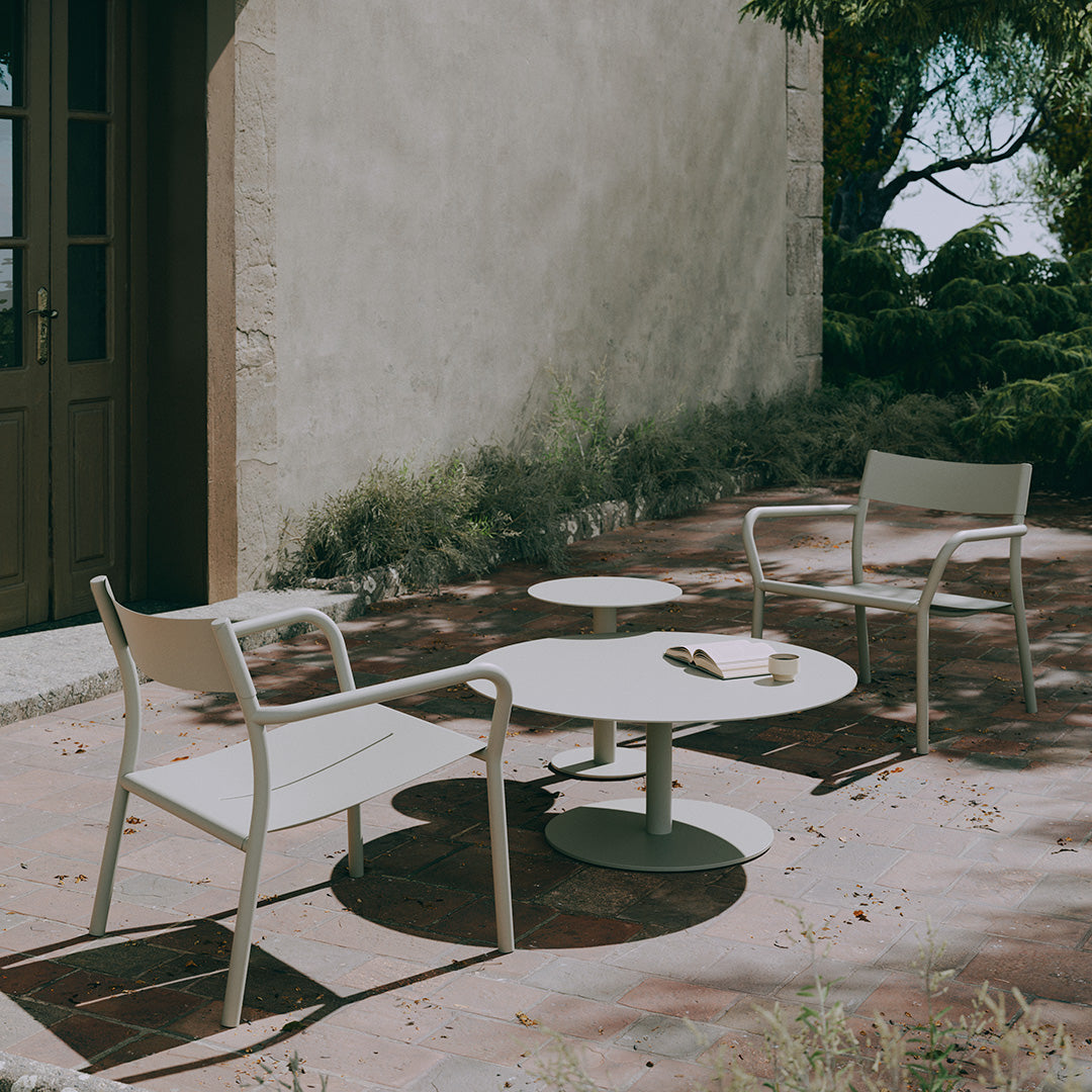 Light beige outdoor furniture set with a round table and two armchairs, featuring clean lines and a minimalist design.