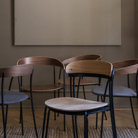 "Set of modern chairs featuring wooden backs and gray seats, with sleek black metal legs against a neutral backdrop."