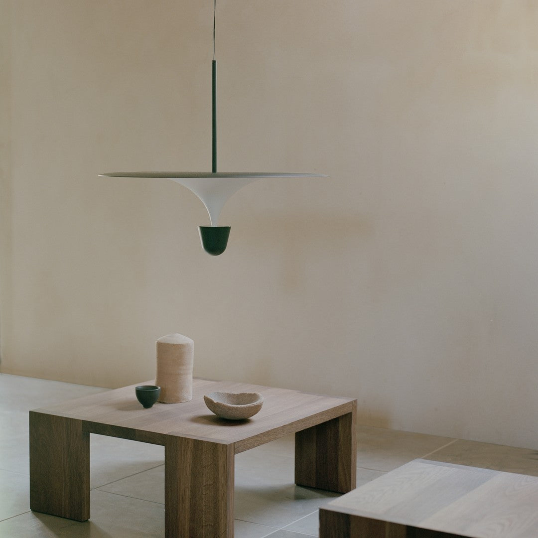 Modern white pendant light with green accents, featuring sleek lines against a soft beige background.