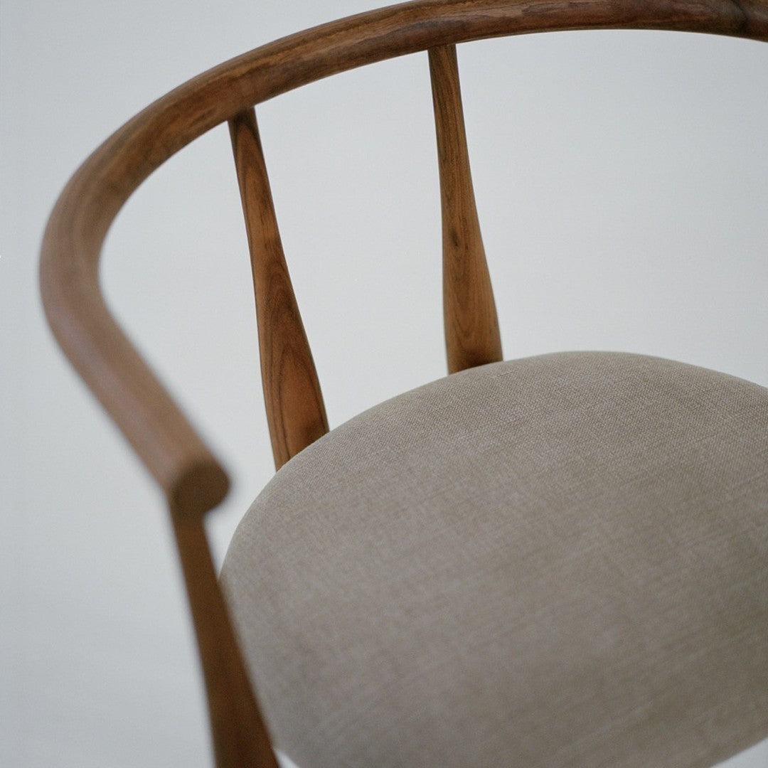 Close-up of a wooden chair with a beige cushion on a plain background