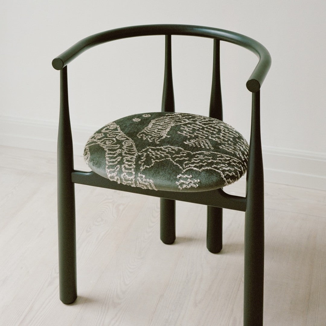 Green chair with patterned cushion on a light wooden floor