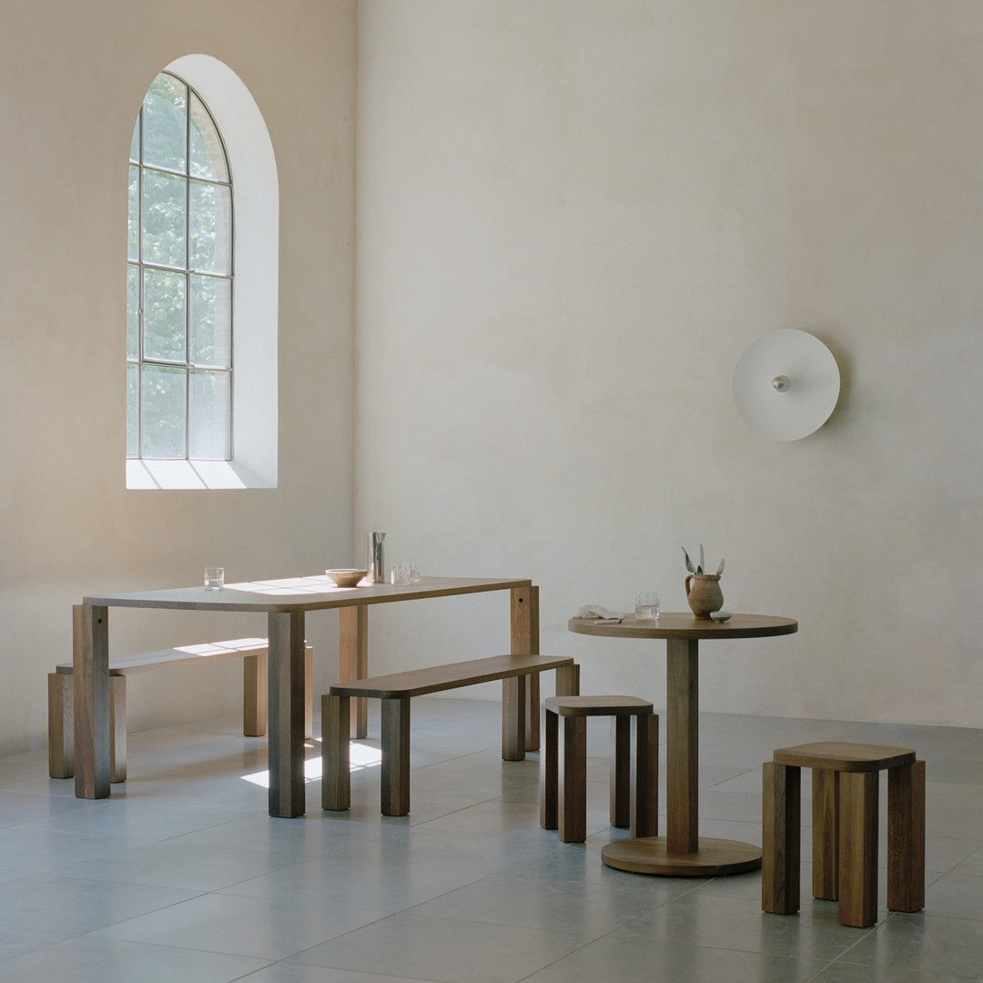 Natural wood furniture with warm brown tones and light gray flooring, set against a soft beige wall.