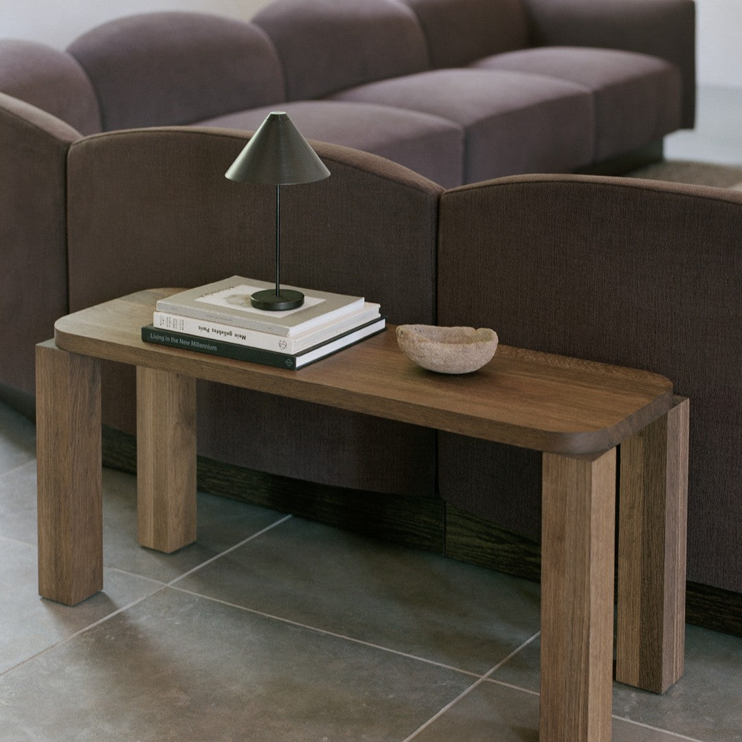 Wooden bench with natural tones, paired with dark purple upholstery and gray tiles for a modern aesthetic.