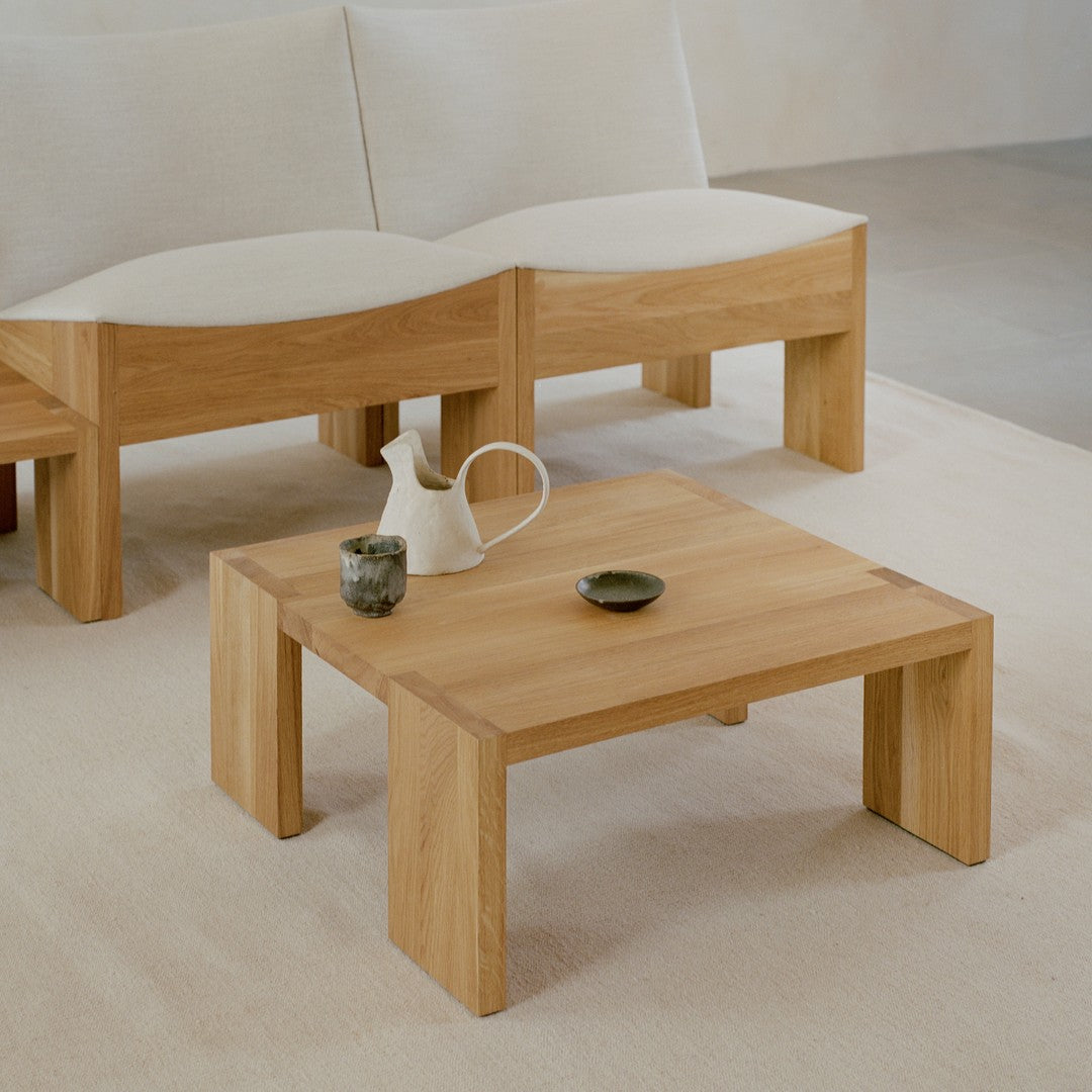 Light beige and natural wood coffee table with clean lines, complemented by soft cream upholstery and dark ceramic accents.
