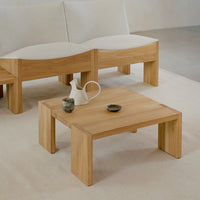 Light beige and natural wood coffee table with clean lines, complemented by soft cream upholstery and dark ceramic accents.