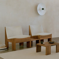 Cream upholstered lounge chairs with natural wood frames in a minimalistic setting. Soft textures and neutral tones.