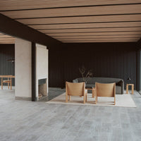 Modern interior with black wooden walls, light gray flooring, and beige furniture featuring smooth wood patterns.