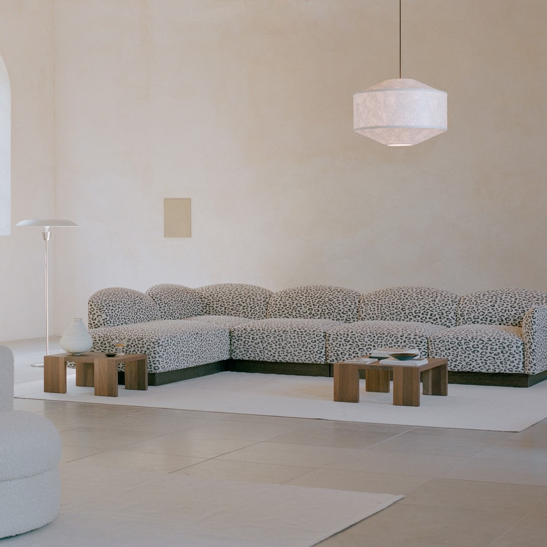 Modern sectional sofa with a beige and black leopard print pattern, in a minimalist interior setting.