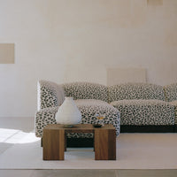 Leopard print sofa in black and white with a wooden coffee table and neutral-toned decor in a minimalist setting.