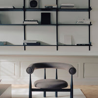 Modern chair in a room with a wall-mounted shelf displaying books and decor items.
