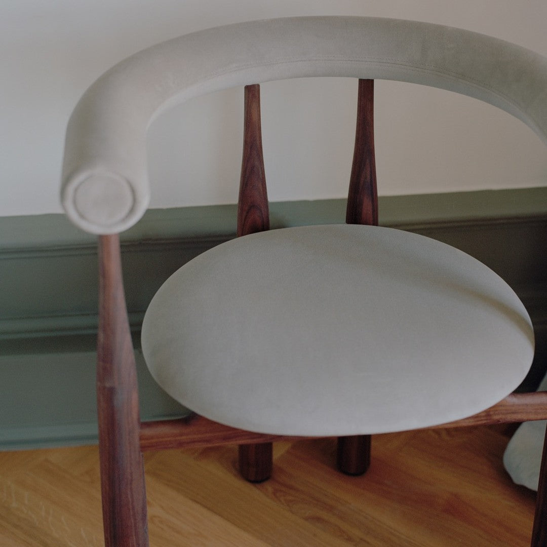 Chair with a green cushion on a wooden floor against a white wall