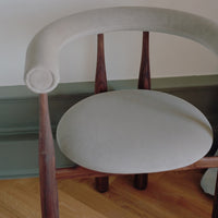 Chair with a green cushion on a wooden floor against a white wall