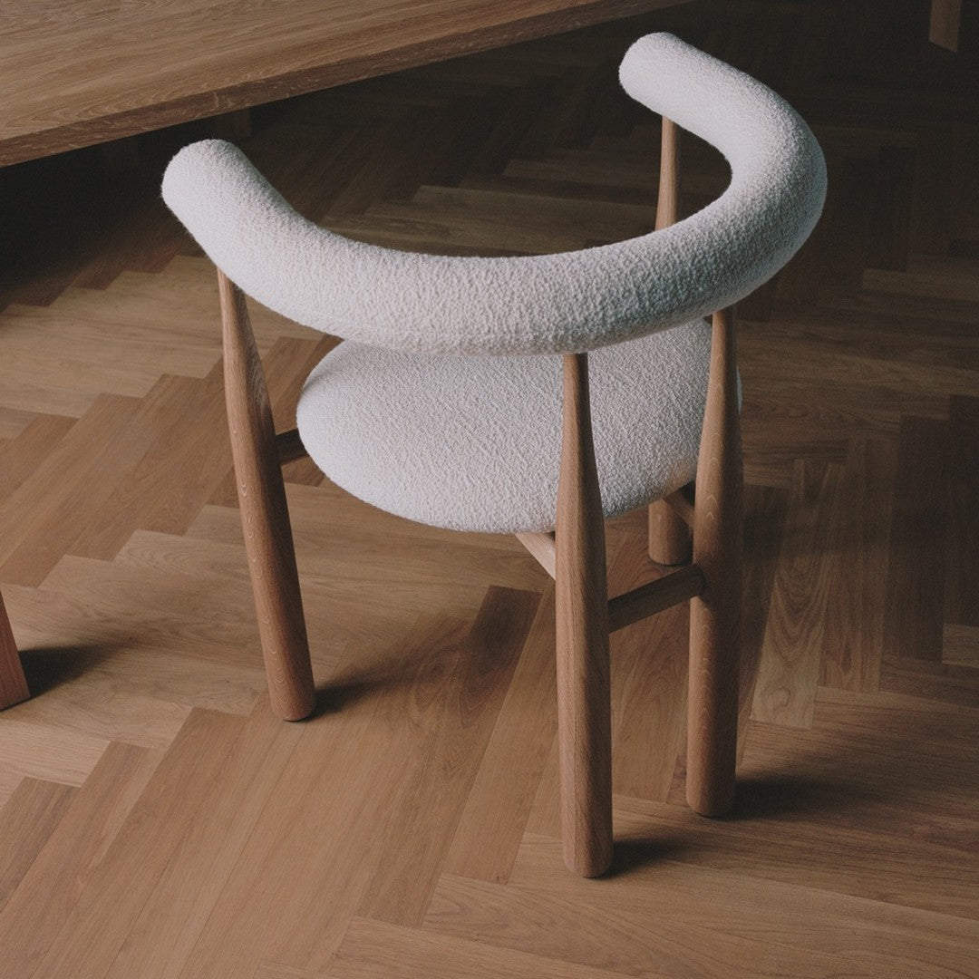 Chair with white cushioned backrest and wooden frame on a wooden floor