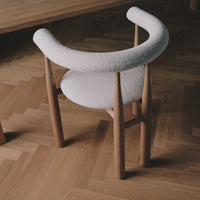 Chair with white cushioned backrest and wooden frame on a wooden floor