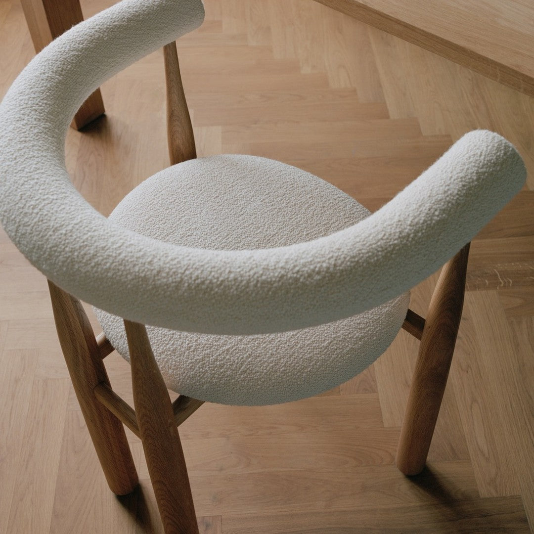 Chair with a textured white seat and wooden frame on a wooden floor.