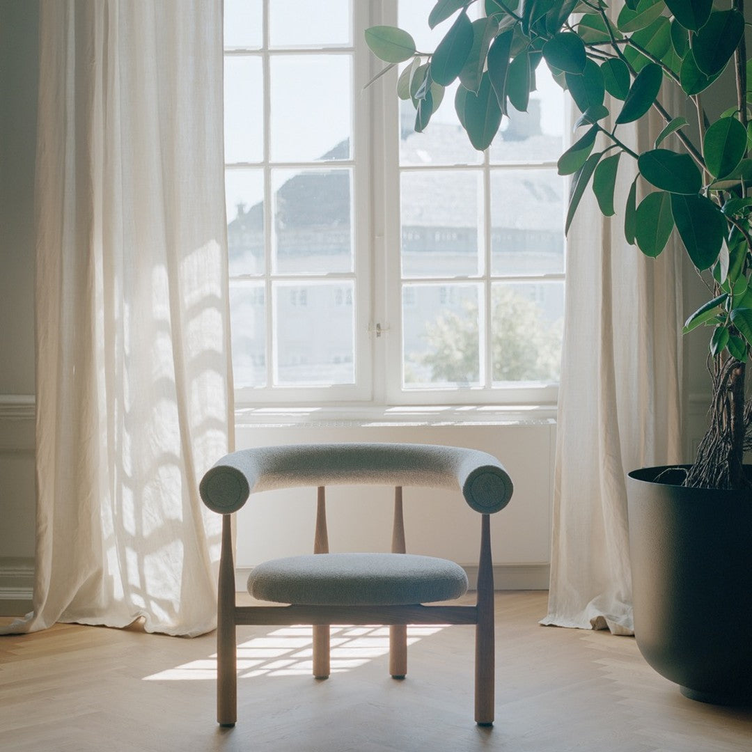 Modern chair in a room with large windows and a potted plant