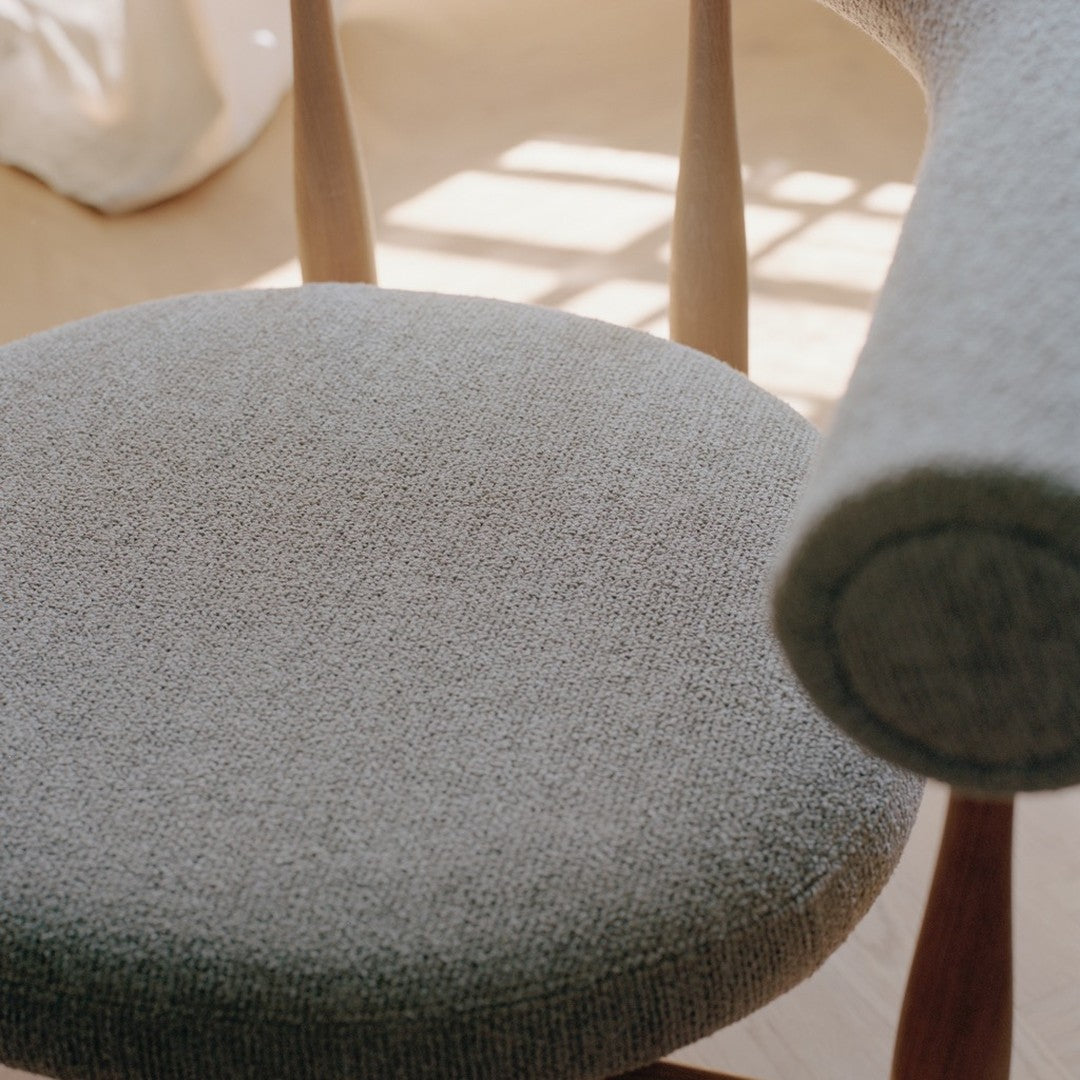 Close-up of a textured gray chair seat with wooden legs.