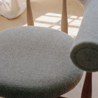 Close-up of a textured gray chair seat with wooden legs.