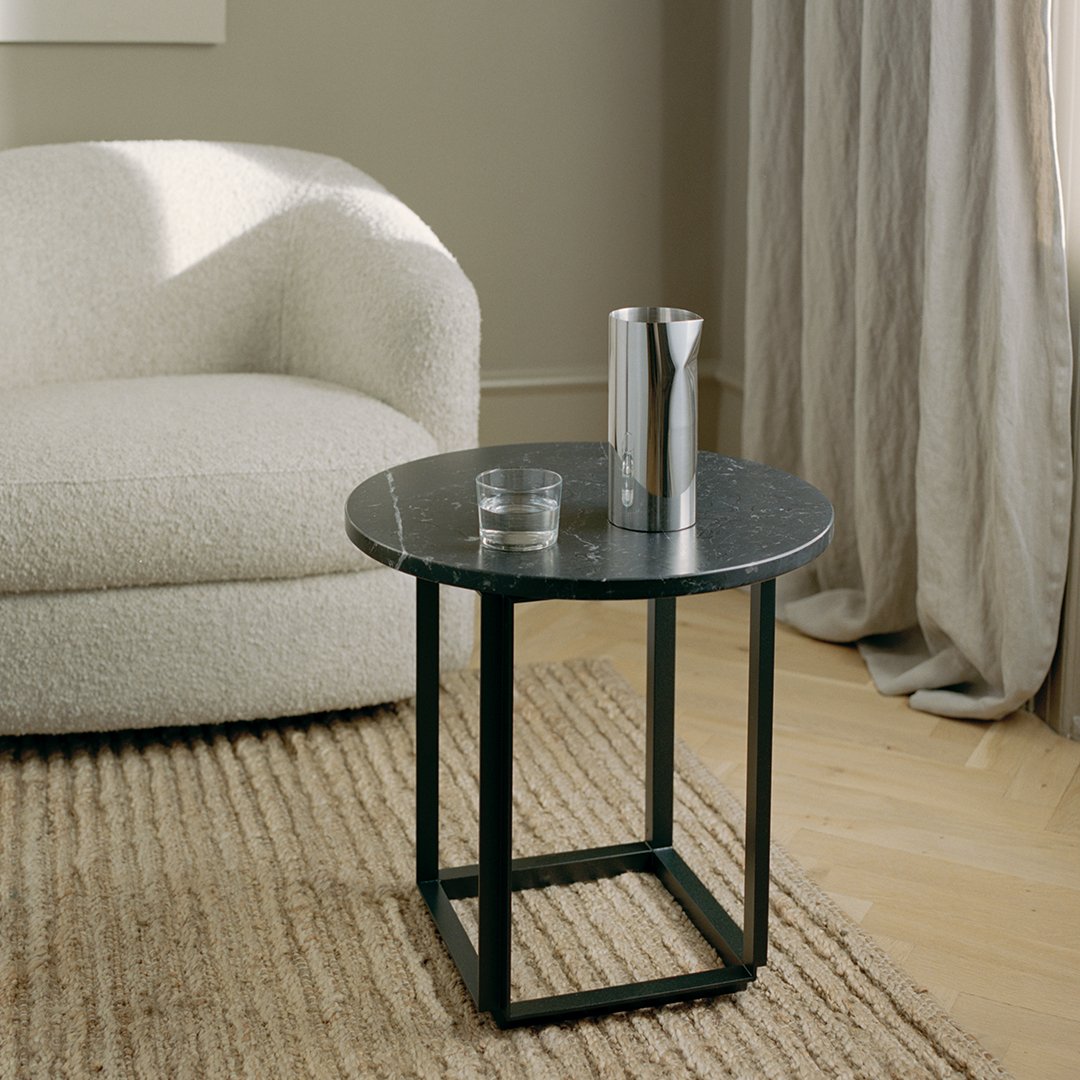 Stylish black marble top side table with a sleek black frame, paired with a light beige textured rug.