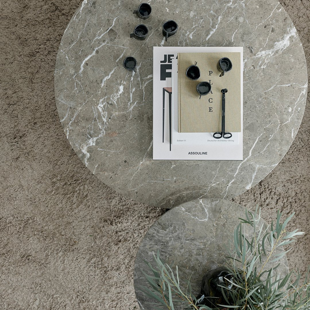 Gray marble table with a magazine and black decorative items, featuring soft earthy tones for a modern aesthetic.