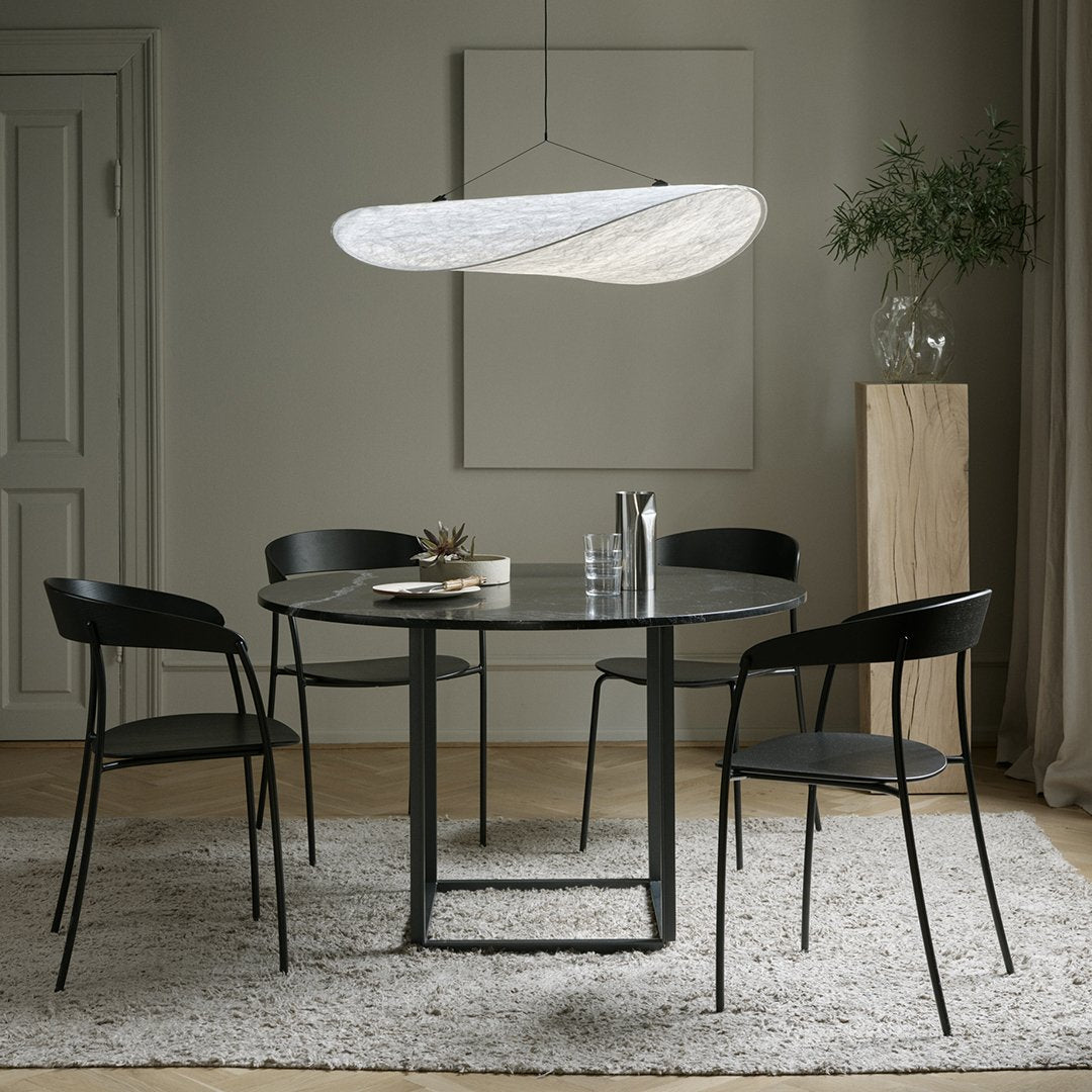 "Round black dining table with sleek chairs, featuring neutral walls and soft gray rug, highlighted by a modern pendant light."