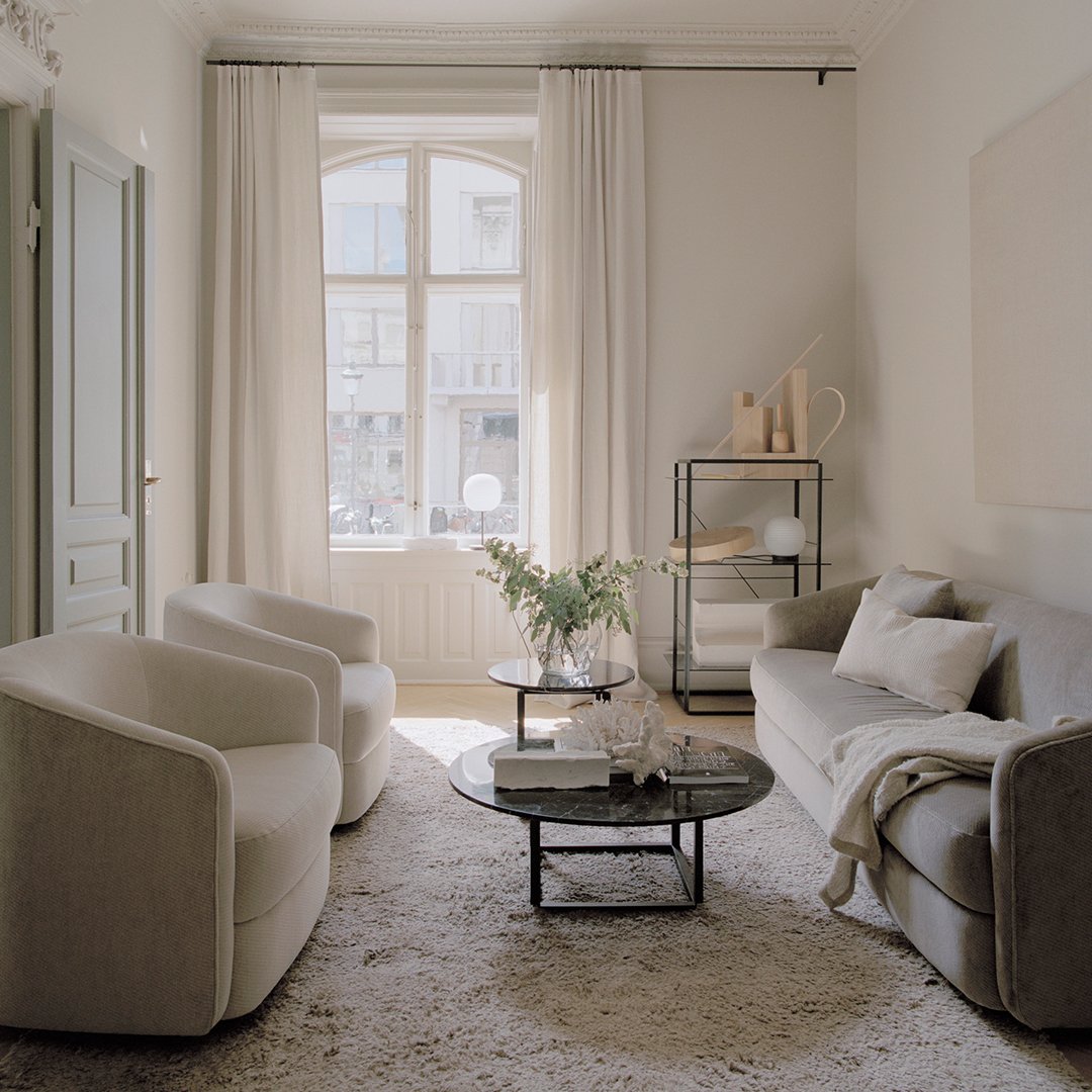 Elegant beige and gray living room with soft textures, light curtains, and a minimalist black coffee table.