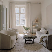 Elegant beige and gray living room with soft textures, light curtains, and a minimalist black coffee table.